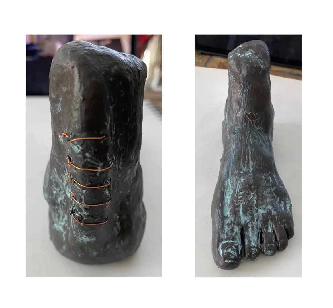 A bronze statue of a foot and a hand.