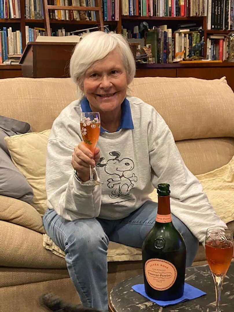 A woman sitting on the couch holding a glass of beer.